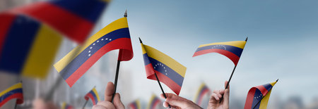 Venezuela flags in their hands on a blurred urban backgroundの写真素材
