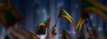 Grenada flags in their hands on a blurred urban backgroundの写真素材