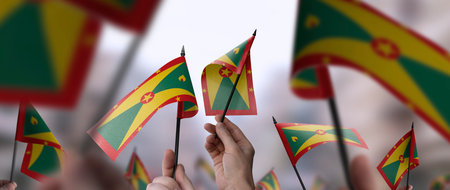 Grenada flags in their hands on a blurred urban backgroundの写真素材