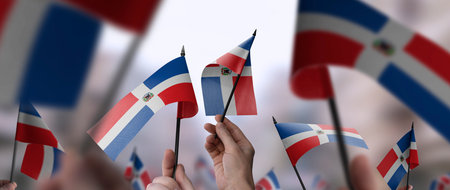 Dominicana flags in their hands on a blurred urban backgroundの写真素材