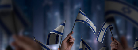 Israel flags in their hands on a blurred urban backgroundの写真素材
