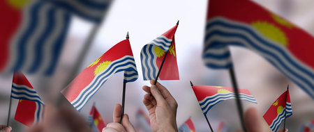 Kiribati flags in their hands on a blurred urban backgroundの写真素材