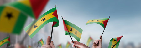 Sao Tome and Principe flags in their hands on a blurred urban backgroundの写真素材