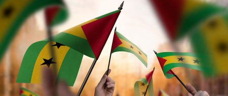 Sao Tome and Principe flags in their hands on a blurred urban backgroundの写真素材