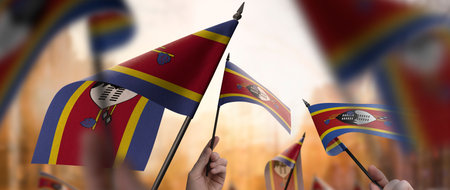 Swaziland flags in their hands on a blurred urban backgroundの写真素材