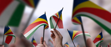 Seychelles flags in their hands on a blurred urban backgroundの写真素材