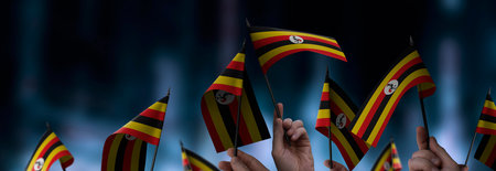 Uganda flags in their hands on a blurred urban backgroundの写真素材