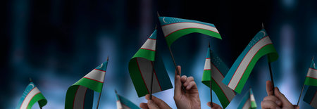 Uzbekistan flags in their hands on a blurred urban backgroundの写真素材