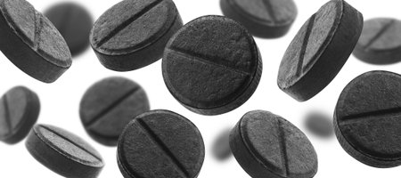 Black activated carbon tablets levitate on a white backgroundの写真素材