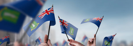 British Virgin Islands flags in their hands on a blurred urban backgroundの写真素材