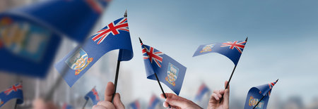 Falkland Islands flags in their hands on a blurred urban backgroundの写真素材