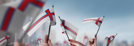 Faroe Islands flags in their hands on a blurred urban backgroundの写真素材