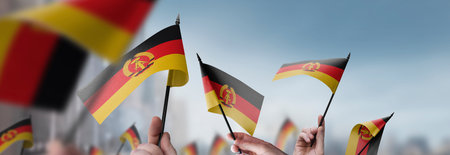 GDR flags in their hands on a blurred urban backgroundの写真素材