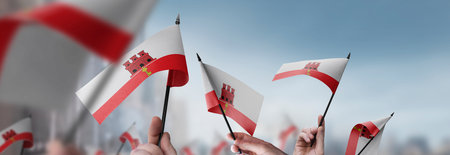 Gibraltar flags in their hands on a blurred urban backgroundの写真素材