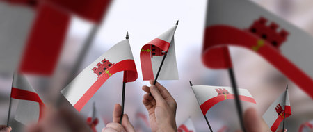Gibraltar flags in their hands on a blurred urban backgroundの写真素材