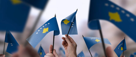 Kosovo flags in their hands on a blurred urban background