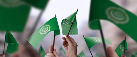 Arab League flags in their hands on a blurred urban background