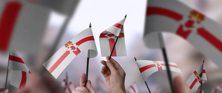 Northern Ireland flags in their hands on a blurred urban background