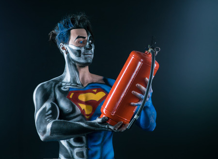 Bodyart of a super hero holding a fire extinguisher in the handsの写真素材
