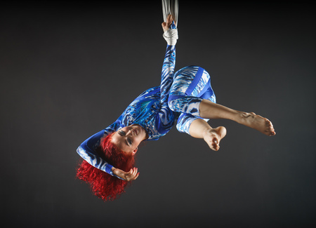athletic sexy aerial circus artist with redhead in blue costume dancing in the air with balanceの写真素材