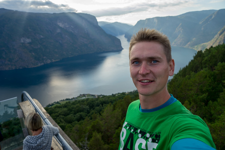 Young traveller taking selfie on the top with Beautiful fjord on background in Norwayの写真素材