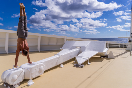 Muscular man standing on huge anchor on the bow of Cruise ship