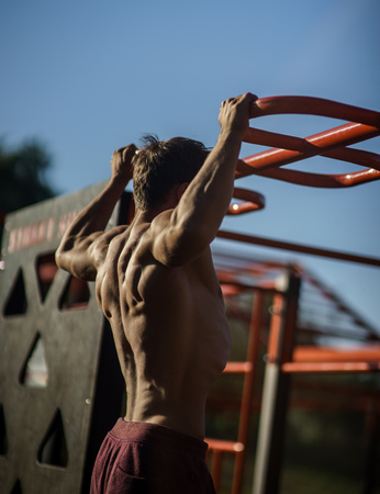 Muscular man during his workout on the street with horizontal barの写真素材