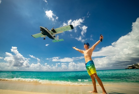 Man with airplane flying over on famous Maho beach near Princess Juliana International airport. Concept of happy vacation and holidayの写真素材