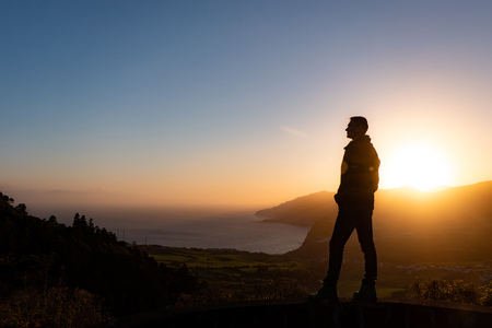 Man in beautiful inspiring sunrise with mountains and sea.の写真素材
