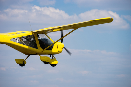 Small yellow private aircraft flying in a blue skyの写真素材