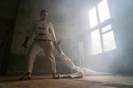 Two crazy men in straitjackets are in an abandoned clinicの写真素材