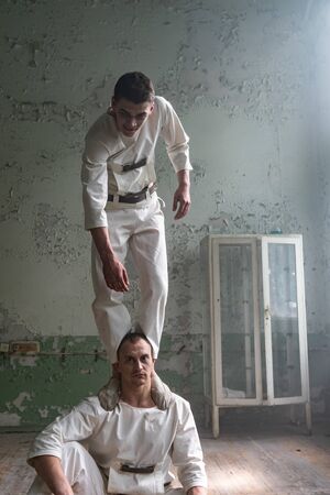 Two crazy men in straitjackets are in an abandoned clinicの写真素材