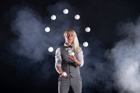 Juggler wearing a suit like a businessman throwing white balls. concept of success and managementの写真素材