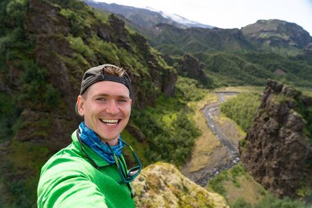 tourist man on the river and green mountains background takes a picture of Selfieの写真素材