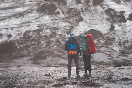 August of 2019. Iceland. Two tourist on background of Black Volcanic Iceland Landscape At...