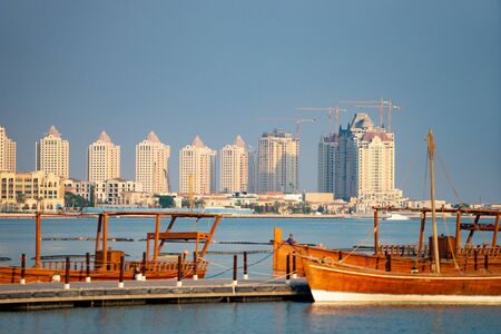 Traditional fishing boat At docked with city on background at long berth with calm blue water.