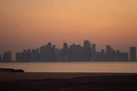 Vibrant Skyline of Doha at dramatick sunset as seen from the opposite side of the capital city bay.の写真素材