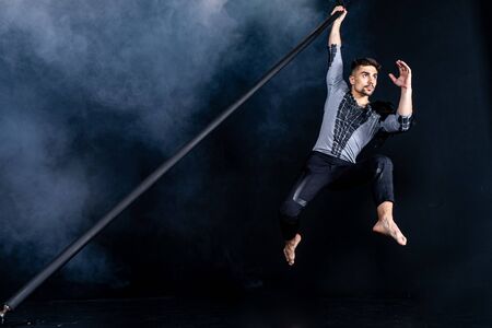 Performance concept. Man hanging on chinese pole. Athlete performing flying pole