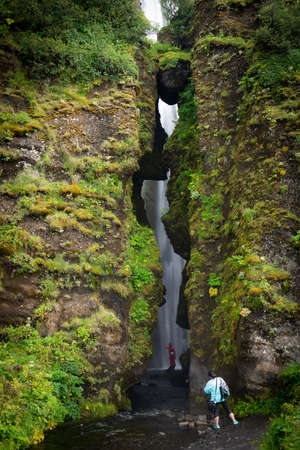 August of 2019. Gljufrabui waterfall, Iceland.on south Iceland. Girl standing in front of entrance to the narrow canyon on the way to the hidden Gljufrabui waterfallのeditorial素材