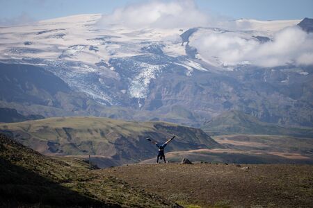 young guy standing on his hands with snowy mountain and glacier background on the way of Laugavegur...