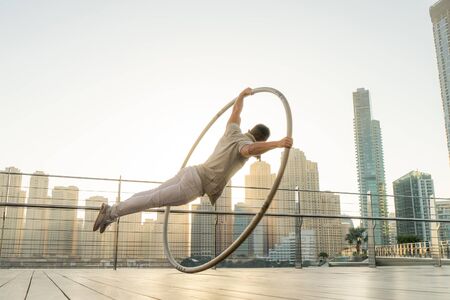 Cyr Wheel artist with cityscape background of Dubai during sunset.
