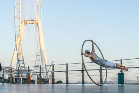 Dubai, February 2020. Cyr Wheel artist with Ferris wheel on background of Dubai during sunset