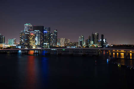 Miami city skyline panorama at dusk with urban skyscrapers and bridge over sea with reflectionの写真素材