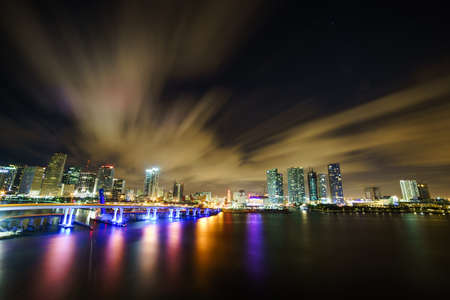 Miami city skyline panorama at dusk with urban skyscrapers and bridge over sea with reflectionの写真素材
