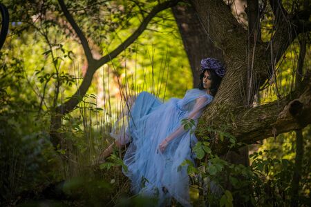 make up of dead bride with black hair dressed wedding clothes lieng on the tree in the forestの写真素材