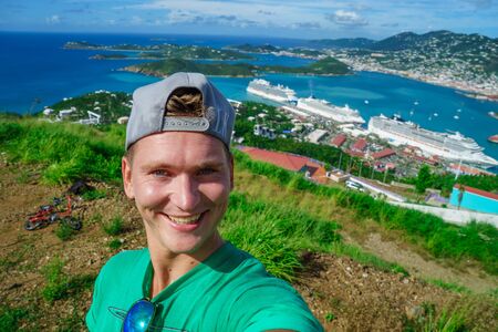 Three cruise ships in the port of St Thomas, US Virgin Islands with smiling tourist foreground