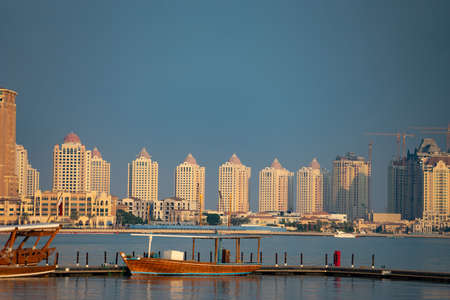 Traditional fishing boat At docked with city on background at long berth with calm blue waterの写真素材