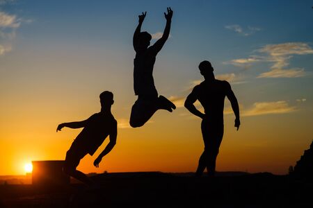 Group Of Happy Young People Jumping On The roof with sunset on backgroundの写真素材