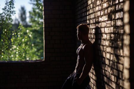 Muscular Shirtless Young Man Inside Abandoned Building. Concept of looking at the featureの写真素材