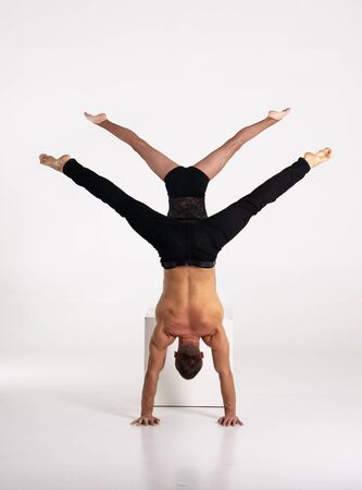 Good shaped man and woman practicing handstand exercise isolated on white background. Strength and motivationの写真素材